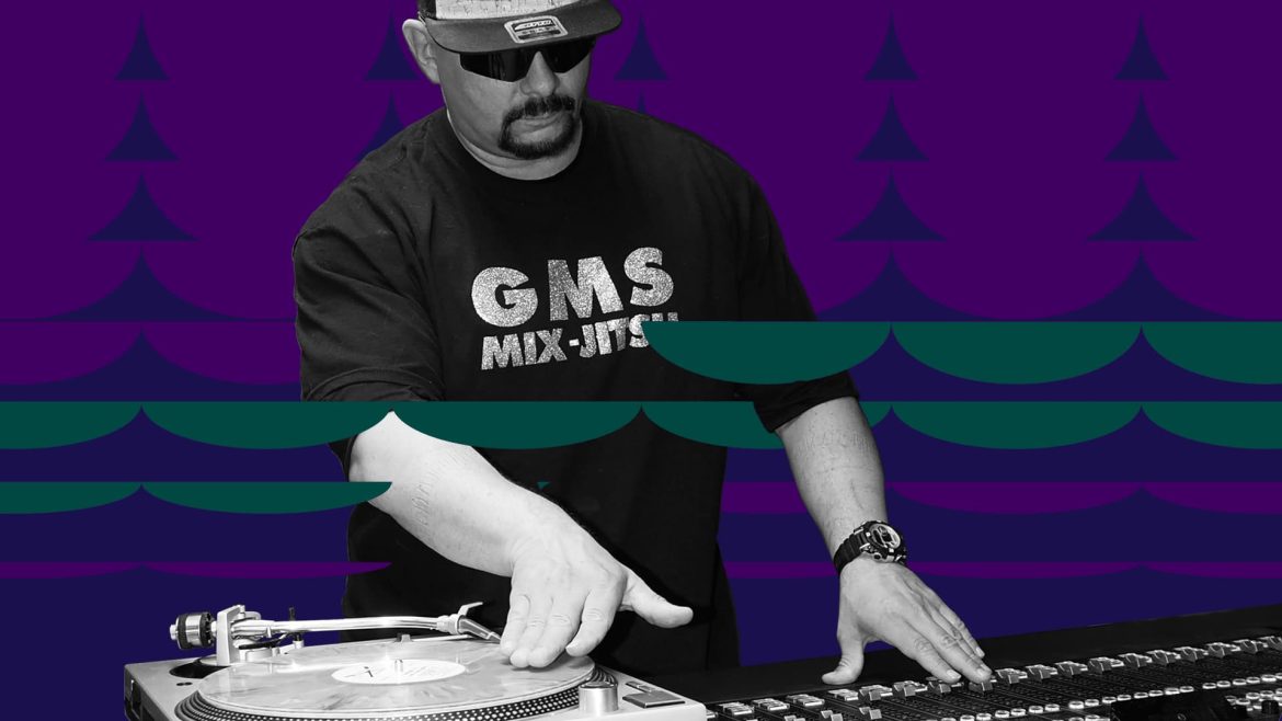 Grandmaster GMS DJs, with one hand on vinyl record and the other on mixer
