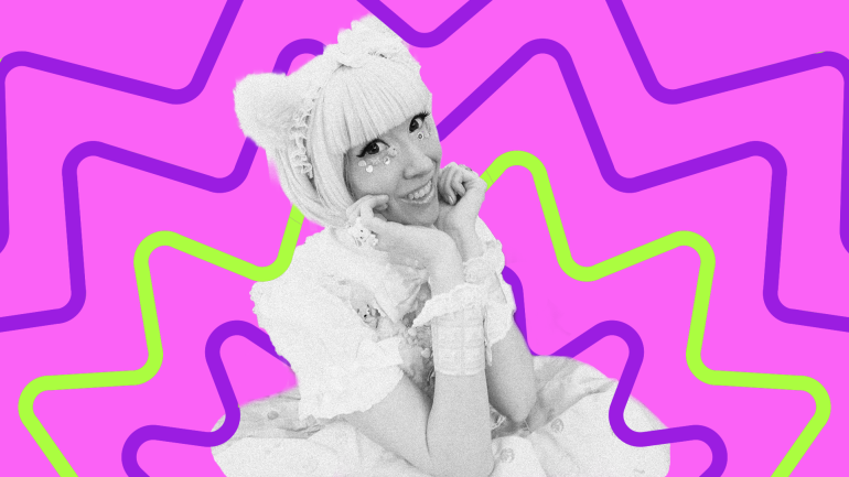 DJ Jimni Cricket smiles while resting chin on hands in vibrant lacey attire
