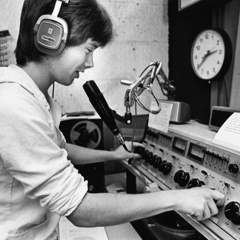 Drew Harlander turns knobs while speaking into mic while wearing headphones