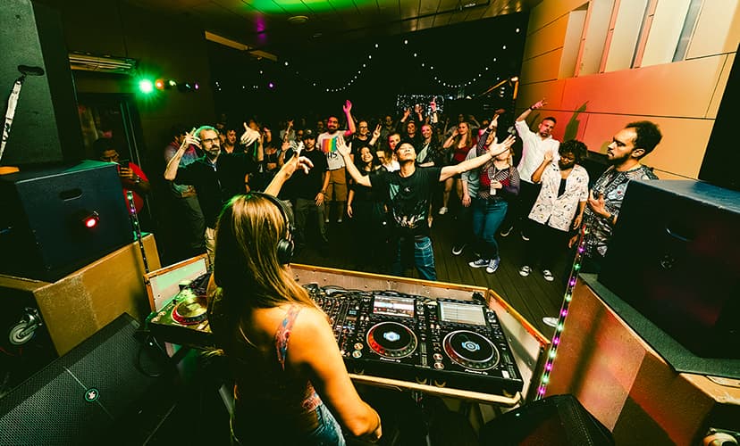 Woman DJs on the deck at Monkey Loft to a dancing crowd